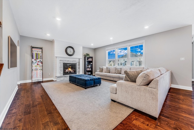 living room featuring a high end fireplace, dark wood finished floors, baseboards, and recessed lighting