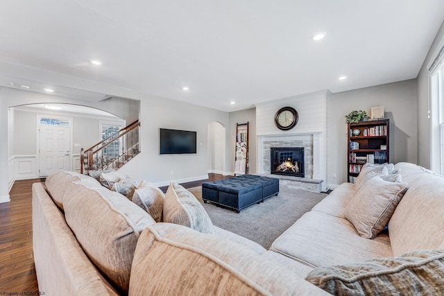 living room with stairway, arched walkways, wood finished floors, and recessed lighting