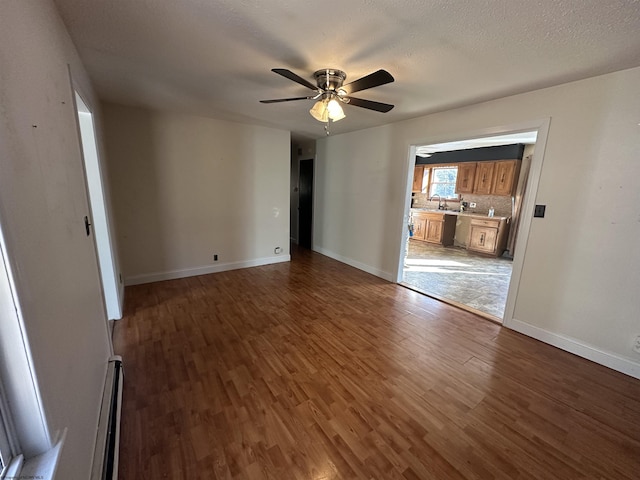 unfurnished living room with a baseboard radiator, baseboards, ceiling fan, and wood finished floors