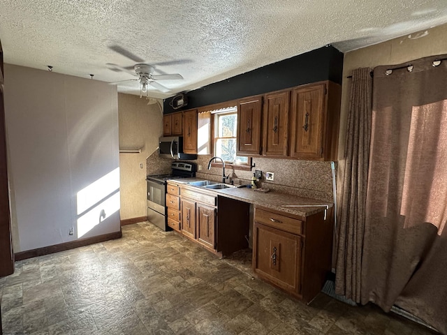 kitchen featuring tasteful backsplash, appliances with stainless steel finishes, a sink, ceiling fan, and baseboards