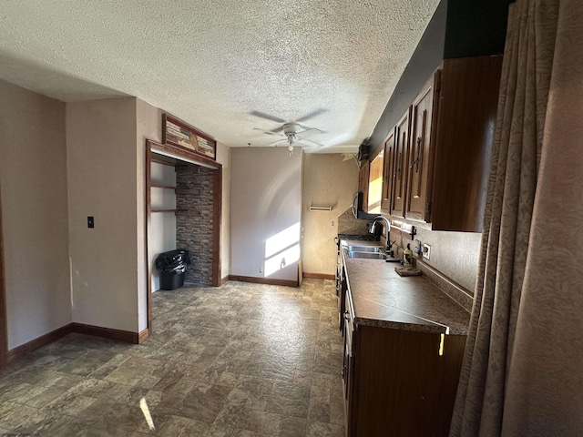kitchen featuring ceiling fan, baseboards, dark brown cabinets, and a sink