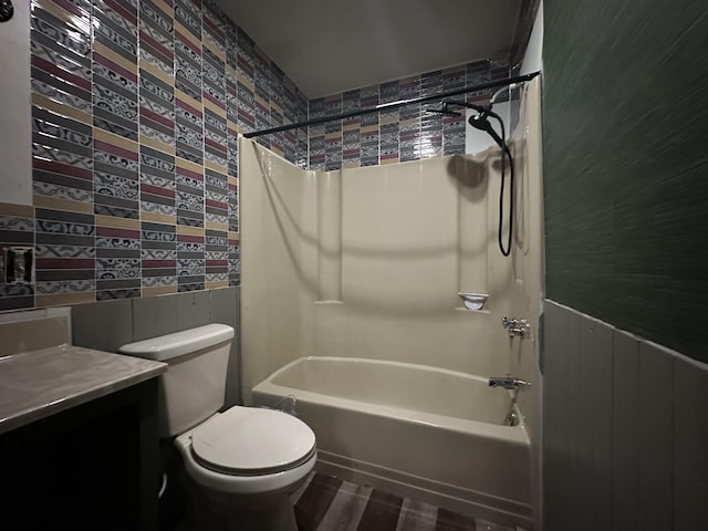 bathroom with toilet, a wainscoted wall, vanity, and shower / bathing tub combination