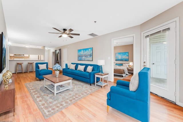 living area with ceiling fan, wood finished floors, and visible vents