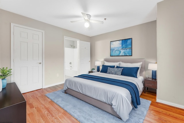 bedroom featuring light wood-style flooring, baseboards, a ceiling fan, and ensuite bathroom