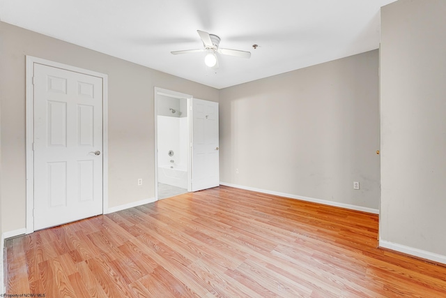 unfurnished bedroom with light wood-style floors, a ceiling fan, baseboards, and connected bathroom