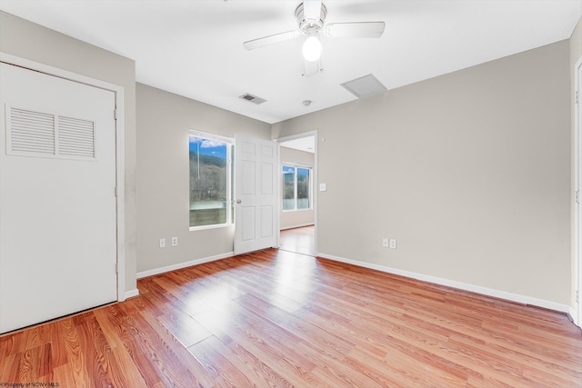 unfurnished room with light wood-style flooring, a ceiling fan, visible vents, and baseboards