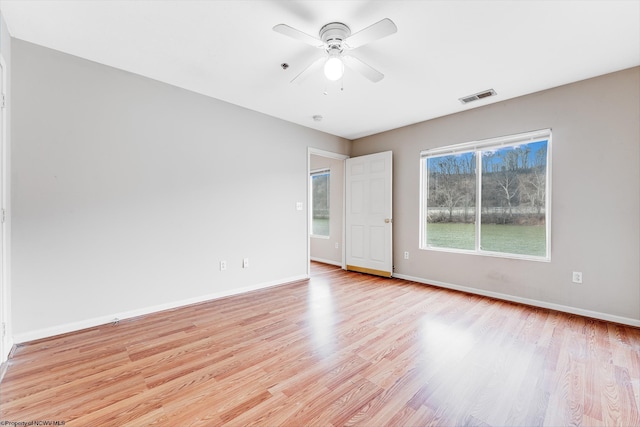 empty room featuring ceiling fan, light wood-style flooring, visible vents, and baseboards