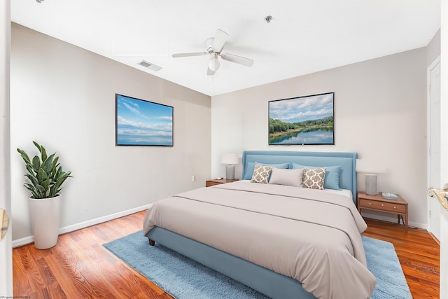 bedroom with a ceiling fan, baseboards, visible vents, and wood finished floors