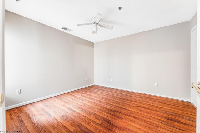 empty room with a ceiling fan, baseboards, visible vents, and wood finished floors