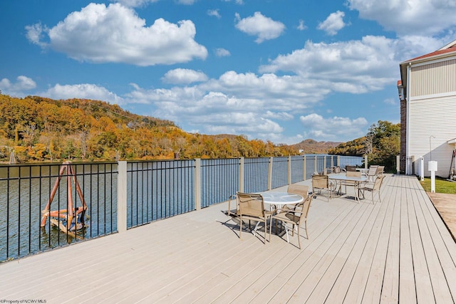 wooden deck featuring a forest view, a water and mountain view, and outdoor dining space