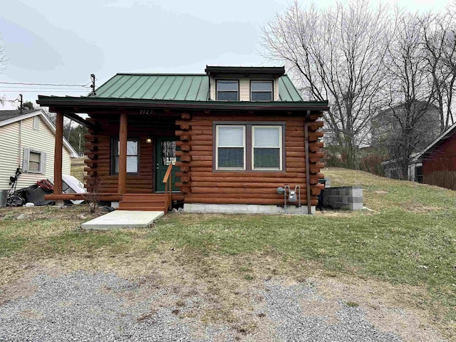 log cabin with a standing seam roof, metal roof, log exterior, and a front yard