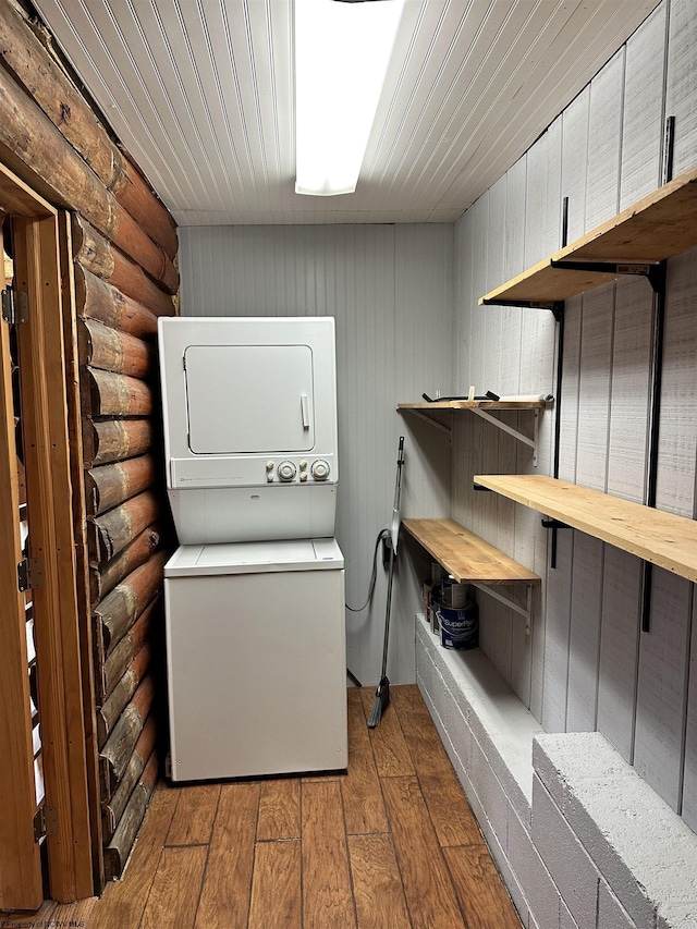 washroom with rustic walls, stacked washing maching and dryer, laundry area, wooden ceiling, and hardwood / wood-style floors