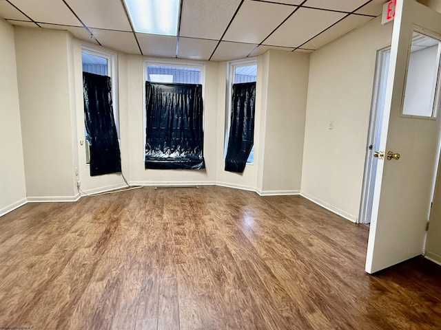 spare room featuring a paneled ceiling, baseboards, and wood finished floors