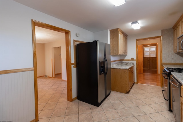 3508 Old Mill Rd, Weston, WV 26452 - kitchen with light tile patterned floors, gas range oven, fridge with ice dispenser, and a wainscoted wall