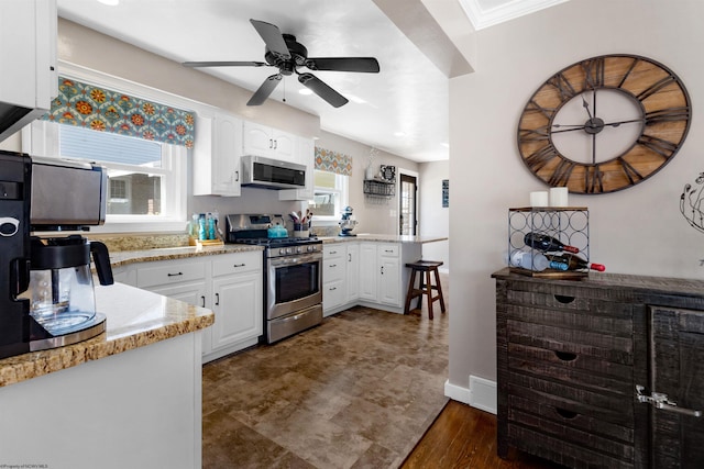 kitchen with dark wood finished floors, appliances with stainless steel finishes, white cabinets, ceiling fan, and a peninsula