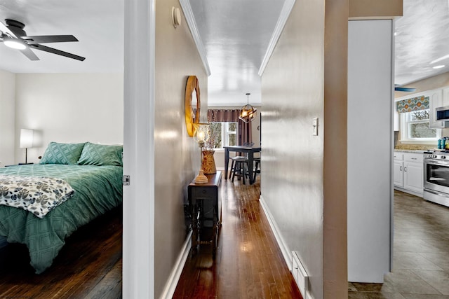 hallway with baseboards, wood finished floors, visible vents, and crown molding