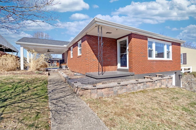 view of home's exterior with brick siding, a yard, and ceiling fan