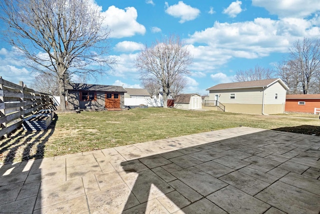 view of yard with an outbuilding, a patio, a storage shed, and fence