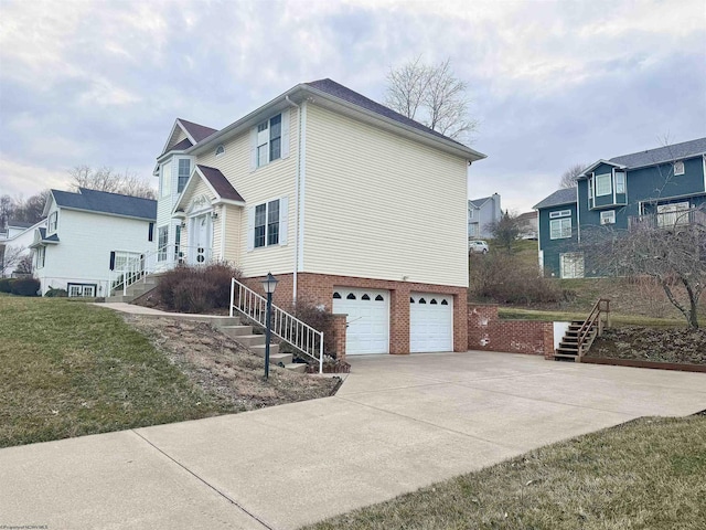 view of home's exterior featuring brick siding, concrete driveway, a lawn, a garage, and stairs