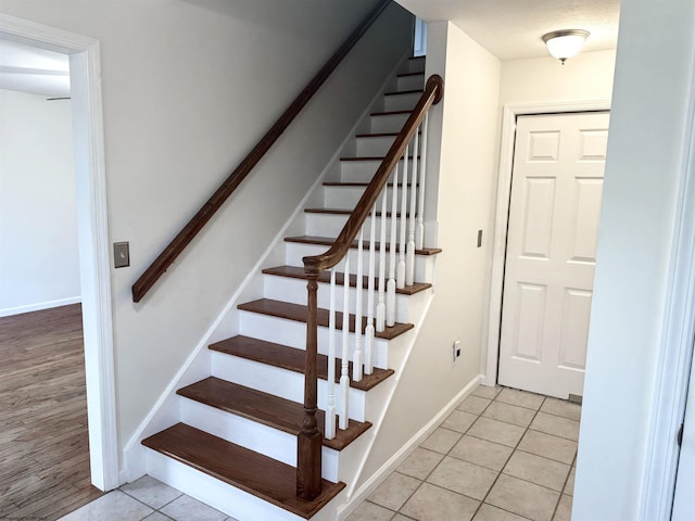 stairway featuring tile patterned flooring and baseboards