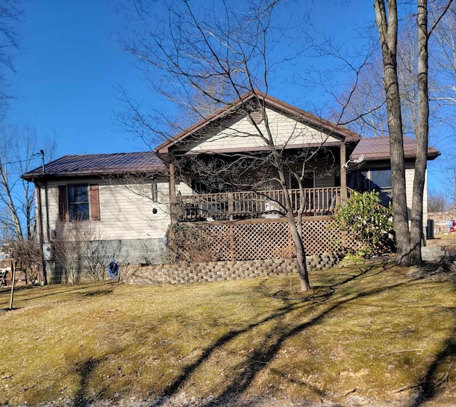 back of house with metal roof and a yard