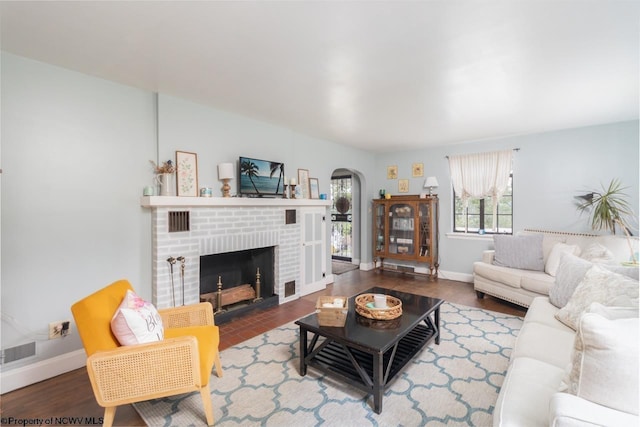 living area featuring visible vents, a fireplace, arched walkways, and baseboards