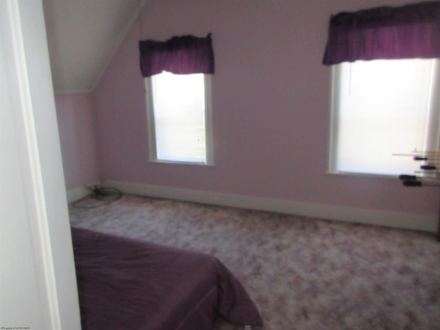 bedroom with lofted ceiling, carpet flooring, and baseboards