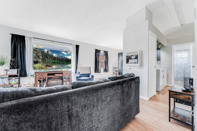 living area featuring light wood-style floors, vaulted ceiling, baseboards, heating unit, and washer and clothes dryer