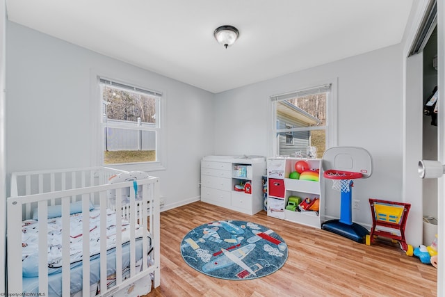 bedroom featuring multiple windows, baseboards, and wood finished floors