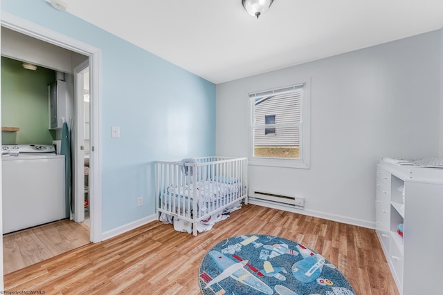 bedroom featuring washer / dryer, a baseboard radiator, baseboards, and wood finished floors