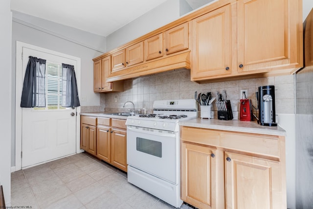 kitchen with white range with gas cooktop, a sink, and light brown cabinetry