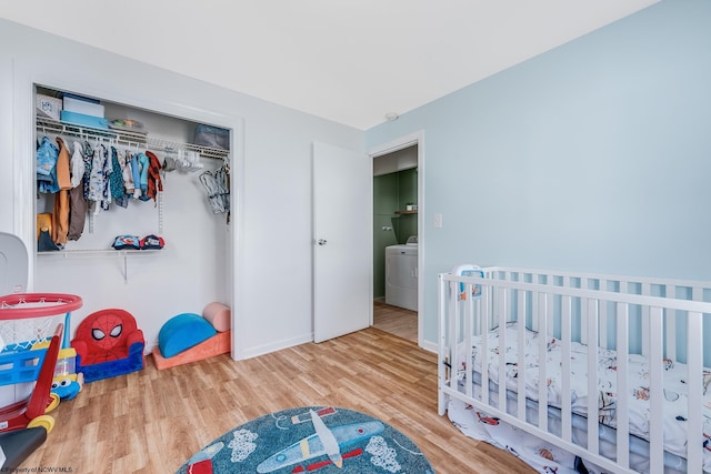 bedroom featuring washer / dryer, a closet, baseboards, and wood finished floors