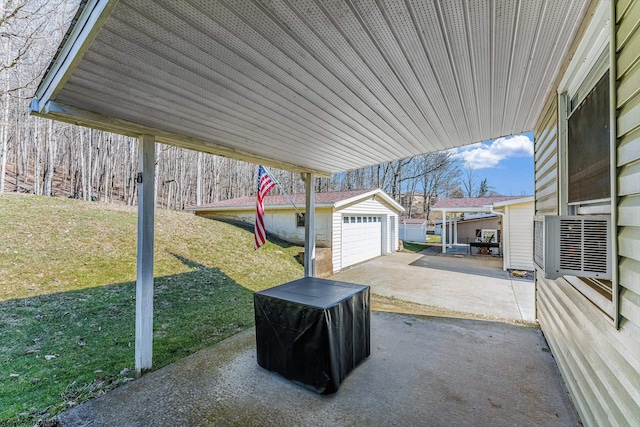 view of patio featuring driveway, a detached garage, and an outdoor structure