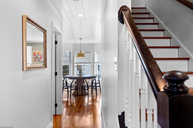 staircase with crown molding, baseboards, and wood finished floors