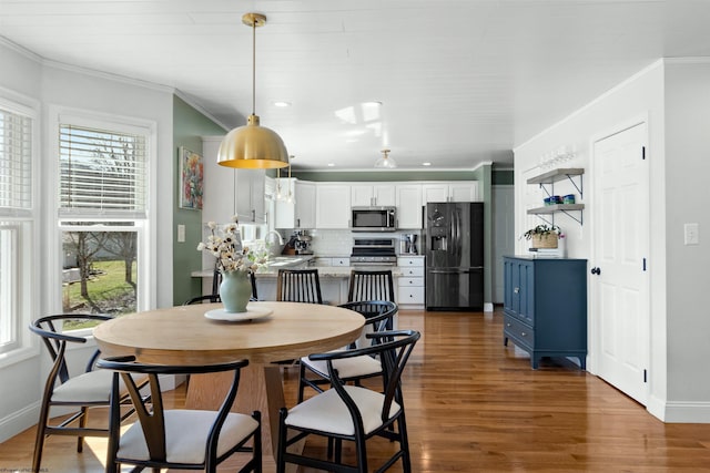 dining space featuring baseboards, wood finished floors, and crown molding