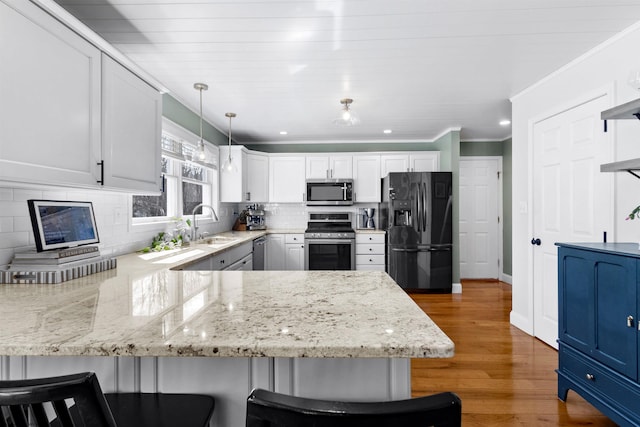 kitchen featuring tasteful backsplash, white cabinets, appliances with stainless steel finishes, ornamental molding, and a peninsula