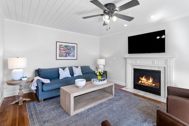 living room featuring baseboards, ornamental molding, wood finished floors, and a high end fireplace