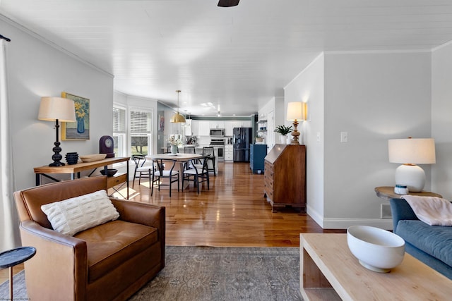 living room with ornamental molding, dark wood-style flooring, and baseboards