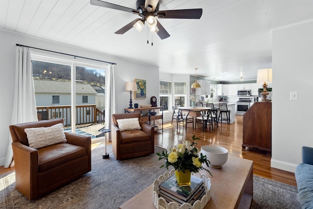 living room with a ceiling fan, wood finished floors, a wealth of natural light, and baseboards