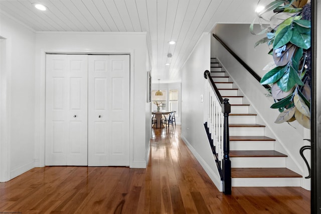 stairway featuring recessed lighting, ornamental molding, wood ceiling, wood finished floors, and baseboards