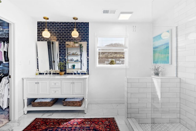 full bath featuring a walk in closet, marble finish floor, double vanity, visible vents, and a sink