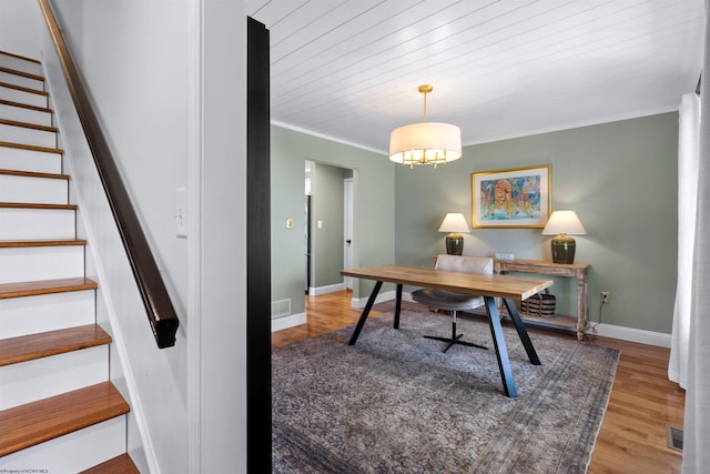 office featuring a notable chandelier, wood finished floors, visible vents, baseboards, and ornamental molding