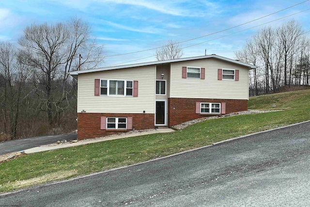 view of front facade featuring driveway, a front lawn, and brick siding