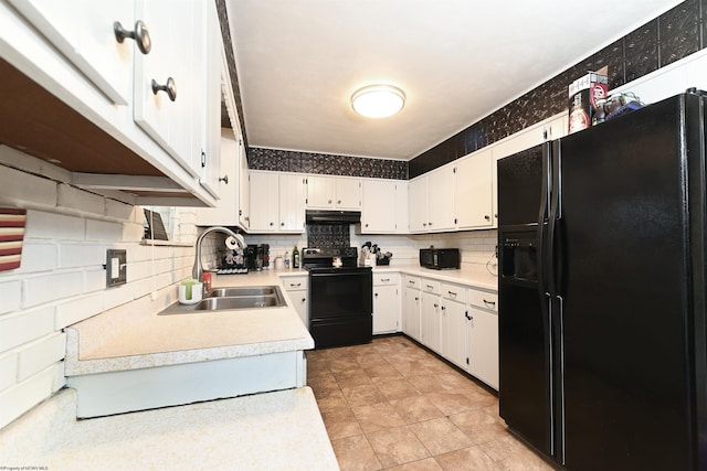 kitchen featuring under cabinet range hood, a sink, light countertops, decorative backsplash, and black appliances