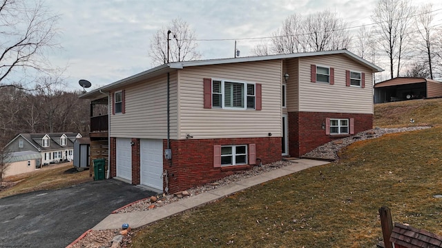 view of home's exterior with driveway, brick siding, a lawn, and an attached garage