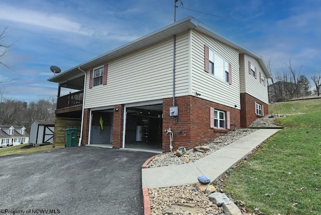 view of front facade featuring aphalt driveway, brick siding, a balcony, and an attached garage