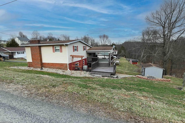 view of front facade with a storage shed, a chimney, a deck, an outdoor structure, and a front yard