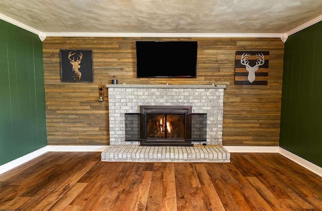 room details with baseboards, a fireplace, ornamental molding, and wood finished floors