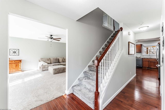 staircase with a ceiling fan, hardwood / wood-style flooring, and baseboards