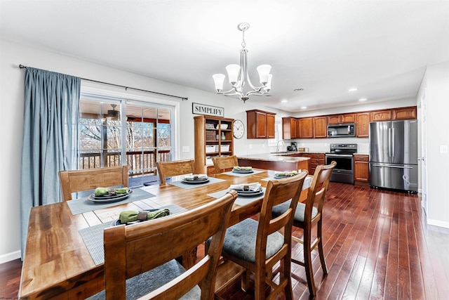 dining space featuring dark wood-style floors, baseboards, and an inviting chandelier